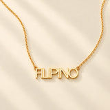FLEURENZ FILIPINO uppercase 14k gold-filled nameplate necklace on an ivory background